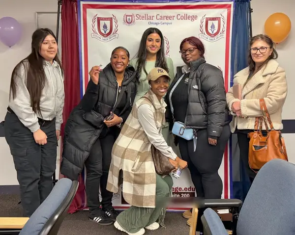 Alina Asif with new students at a meet and greet, one holding up a pin, Stellar Career College Chicago campus
